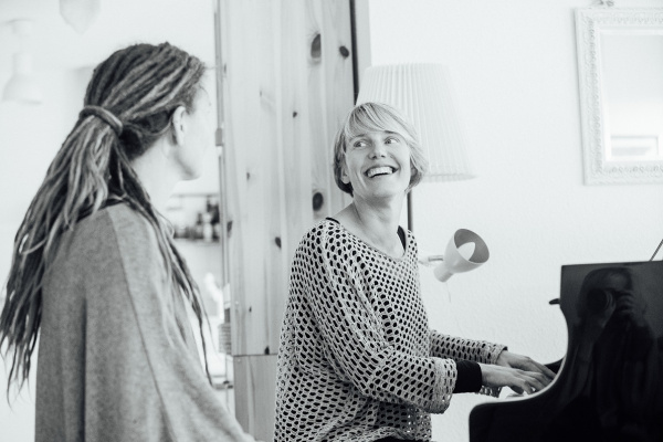 Zwei Frauen machen Musik, eine sitzt am Klavier