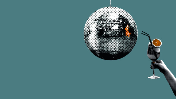 Frau hält Cocktailglas vor glänzernder Diskokugel vor blauem Himmel.