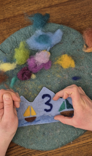 Hände, die eine Geburtstagskrone aus Filz gestalten. 