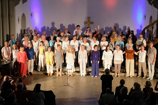 Alle Sängerinnen und Sänger stehen mit den Chorleitern auf der Bühne. 