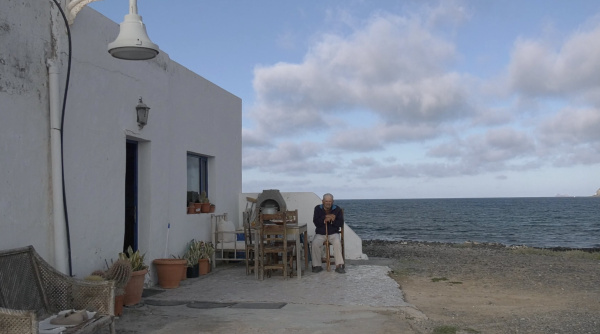 Alter Dorfbewohner sitzt vor seinem Haus am Meer auf einem Stuhl